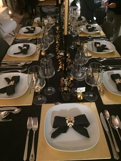 the table is set with black and gold place settings