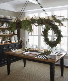 a dining room table is decorated with wreaths and greenery for the holiday season