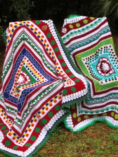 two crocheted blankets sitting on the grass