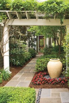 an outdoor garden with lots of greenery and plants on the side of the house