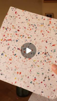 a person holding up a piece of paper with sprinkles on the inside