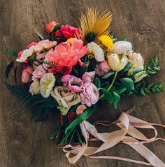 a bouquet of flowers sitting on top of a wooden floor next to a white ribbon