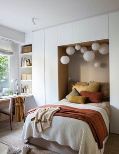 a bedroom with a bed, bookshelf and desk in front of the window