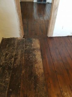 an old wooden floor with peeling paint on it and a cat sitting in the doorway