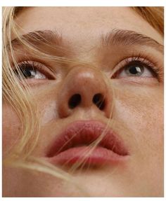 a close up of a woman's nose with her hair blowing in the wind