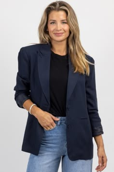 a woman wearing a blue blazer and jeans standing in front of a white background