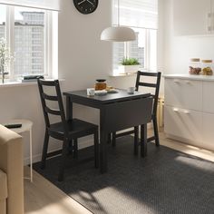 a kitchen table with two chairs and a clock on the wall above it in front of a window