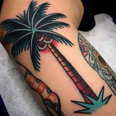 a person with a tattoo on their leg has a palm tree and an arrow in the middle