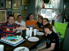 a group of people sitting around a table with a cake