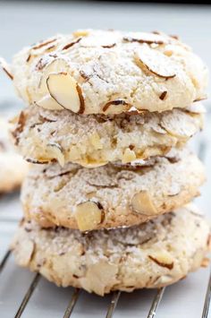 a stack of cookies with almonds and powdered sugar on top, sitting on a cooling rack