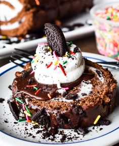 a piece of chocolate cake with ice cream and oreo cookies on top is sitting on a plate