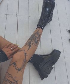 a woman sitting on the floor with her legs crossed and tattoos all over her body