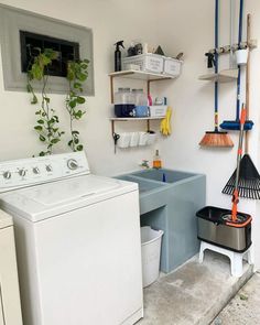 a washer and dryer in a small room with shelves on the wall above them