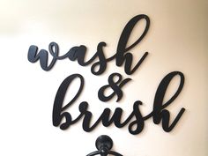 a bathroom sign that says wash and brush on the wall next to a towel dispenser