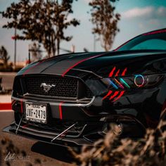 the front end of a black mustang with red and blue stripes on it's hood