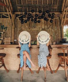 two women sitting at a bar with hats on their heads and one holding a plate