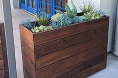 a wooden planter filled with succulents on the side of a building