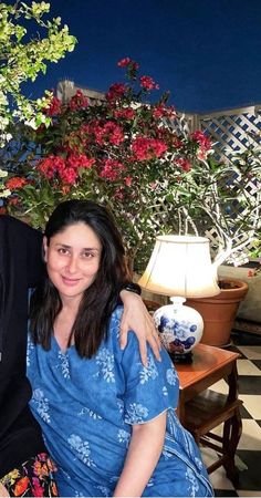 a man and woman sitting next to each other in front of some potted plants