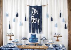 a table topped with blue cakes and tassels next to a sign that says no boys