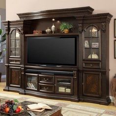 a living room with a large entertainment center in it's centerpiece, and a bowl of fruit on the coffee table