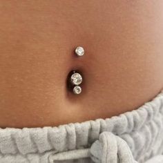 a woman's stomach with three diamond studs on the bottom of her belly