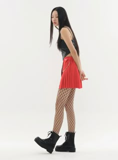 a woman in black top and red skirt with fishnet tights standing on white background