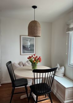 a dining room table with two chairs and a vase filled with flowers on top of it