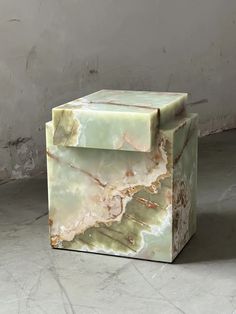 a green marble box sitting on top of a white floor next to a gray wall