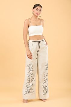 Cosmic latte flared pant with thread embroidery in floral pattern. Paired with belt. - Aza Fashions Beige Floral Embroidered Pants, Embroidered Beige Wide Leg Pants, Embroidered Wide Leg Beige Pants, Embroidered Wide-leg Beige Pants, Floral Embroidered Wide Leg Pants, Floral Embroidered Wide-leg Pants, Linen Embroidery, Pant For Women, Thread Embroidery