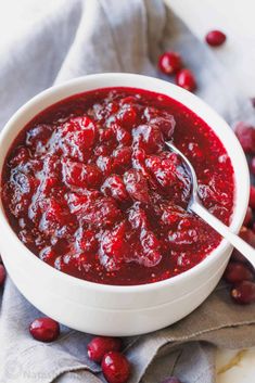 a white bowl filled with cranberry sauce on top of a gray napkin next to red berries