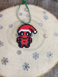 a cross stitch ornament hanging on a wooden slice with snowflakes around it