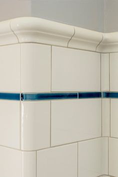 the corner of a white tiled bathroom with blue lines