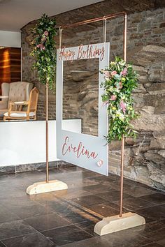 a sign that says happy birthday next to a chair and table with flowers on it