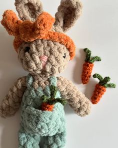 a crocheted bunny with carrots in its hands on a white table top