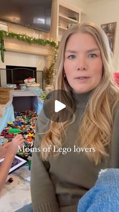 a woman sitting on a couch in front of a fire place with legos all around her