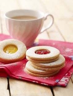 some cookies and jam on a red napkin next to a cup of coffee