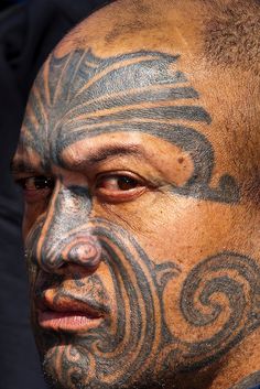 a man with tattoos on his face and neck