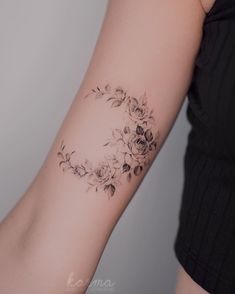 a woman's arm with flowers on it and a circle around the wrist tattoo