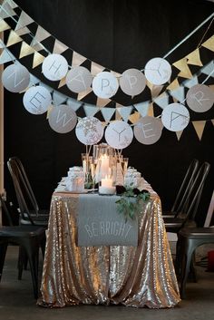 a table topped with lots of cake next to some chairs and tables covered in gold sequins