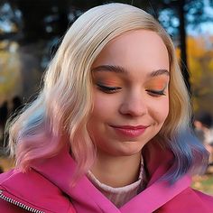 a woman with blonde hair wearing a pink jacket and looking at her cell phone in the park