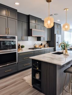 a kitchen with gray cabinets and marble counter tops, gold chandelier hanging from the ceiling