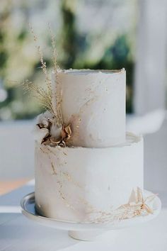 a three tiered white cake with dried flowers on top