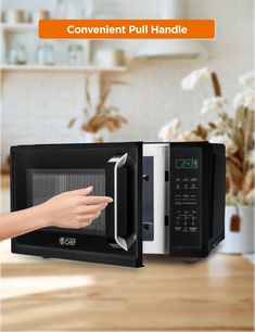 a microwave oven sitting on top of a counter next to a woman's hand