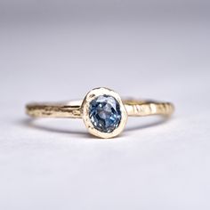 Details: Hand Forged 18k Gold solitaire ring with a beautiful Steely Blue Hand Cut Montana Sapphire. A truly one of a kind ring, old mine cut sapphire cut to the original shape of the rough. Ethically sourced, cut by hand in my Brooklyn Studio.  Set in 18k Recycled Gold, cast in wood and made by hand. Metal: 18K Yellow Gold Stones: Sapphire 0.510ct Montana Sapphire Please note: Each piece is truly unique from every other as a result of the hand forged process. Please expect a genuinely one-of-a- Montana Sapphire Engagement Ring, Montana Sapphire Ring, Sapphire Solitaire Ring, Gold Sapphire Ring, Yellow Rings, Diamond Stacking Rings, Gold Solitaire Ring, Sapphire Solitaire, Blue Stone Ring