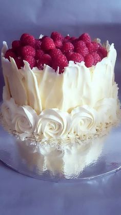 a cake with white frosting and raspberries on top