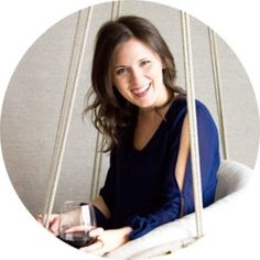 a woman sitting on a swing holding a glass of wine