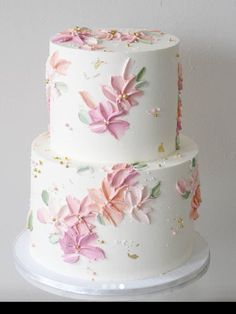 a three layer white cake with pink flowers on it