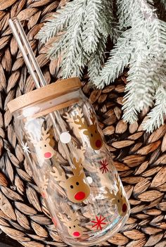 a glass cup with a straw in it sitting on top of a basket next to pine cones