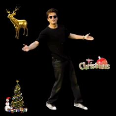 a man in black shirt and sunglasses standing next to a christmas tree with gold reindeer decorations