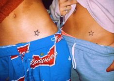 two women with tattoos on their stomachs, one is holding a cell phone and the other has her hand in her pocket